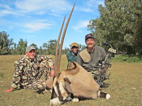 Outfitter Russ Lovemore (left) and tracker/skinner Mike relaxing with the author after the hunt for a beautiful old 37-inch “bonus” gemsbok.